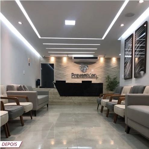 A mesma recepção depois da reforma, com sofás, balcão e forro com iluminação linear.