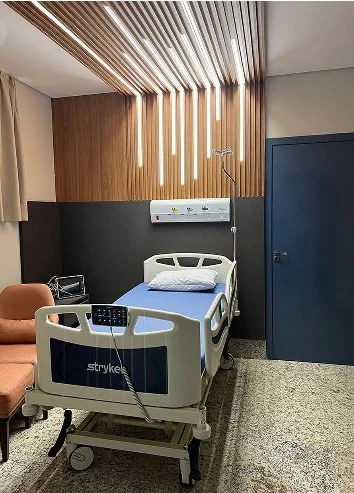 Quarto com leito hospitalar e forro ripado em madeira.