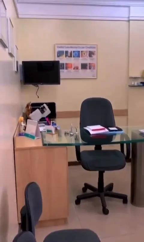 Consultório antes da reforma, com mesa de vidro, cadeiras de escritório e paredes amarelas.
